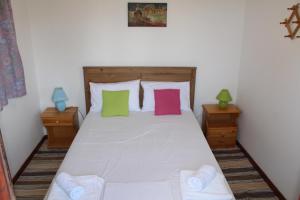 a bedroom with a white bed with colorful pillows at Nikos Seaside Apartments in (( Litherés ))