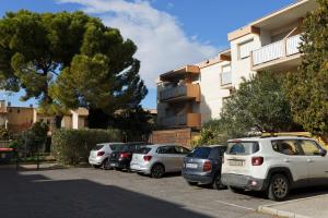 Une rangée de voitures garées dans un parking en face d'un bâtiment dans l'établissement L'écrin, Studio Cosy, MBS, Wifi, Parking, Clim, à Montpellier
