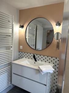 La salle de bains est pourvue d'un lavabo et d'un miroir. dans l'établissement Neptune - SILS, à Douvres-la-Délivrande