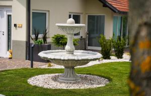 a stone fountain in the grass in a yard at 47 Heaven Luxury House in Radovljica