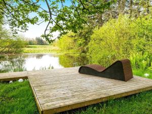 eine Bank auf einem Holzsteg neben einem See in der Unterkunft 8 person holiday home in Henne in Henne