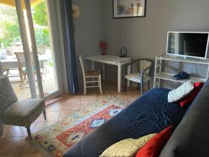 a living room with a couch and a tv at Studio bord de piscine in Sérignan-du-Comtat