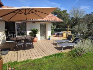 a wooden deck with a table and chairs and an umbrella at Maisonnette neuve plage et commerces à pied in Vieux-Boucau-les-Bains