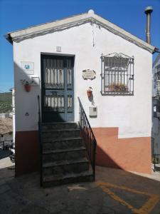 un edificio blanco con una puerta azul y escaleras en La casita de la abuela isabel, en Ubrique