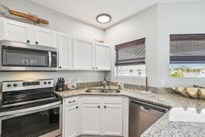 uma cozinha com armários brancos, um lavatório e um micro-ondas em Sandpiper Cove 9232 condo em Destin