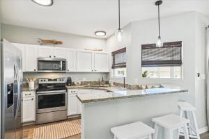 uma cozinha com armários brancos e electrodomésticos de aço inoxidável em Sandpiper Cove 9232 condo em Destin