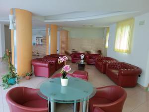 una sala de espera con sofás, mesa y sillas en Residence Queen Mary, en Cattolica