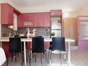 a kitchen with pink cabinets and a table with chairs at Alba Traditional Countryhouse New Anchialos village in Nea Anchialos