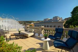 un patio con sillas y mesas en un balcón en Tbilisi Marriott Hotel, en Tiflis