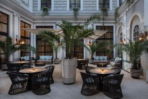 a lobby with tables and chairs and palm trees at Tbilisi Marriott Hotel in Tbilisi City