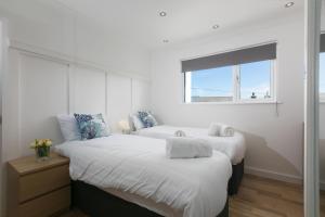 two beds in a room with a window at Willows in St Ives