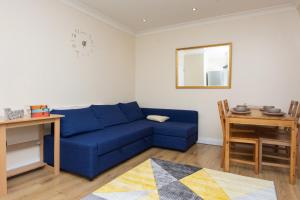 a living room with a blue couch and a table at Evergreen Apartments-Flat 5, London in London