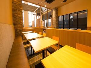 a restaurant with wooden tables and chairs and windows at APA Hotel Namba Ekihigashi in Osaka