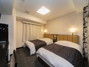 a hotel room with two beds and a television at APA Hotel Namba-Eki Higashi in Osaka