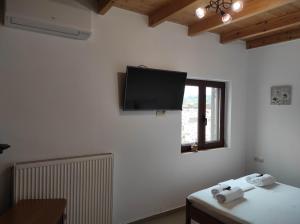 um quarto com uma televisão de ecrã plano na parede em Alexander's cottage em Límni