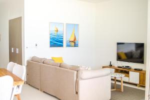 een woonkamer met een bank en een tv bij Summer Breeze - Beachfront - 3 Bedrooms Suite in Pointe d'Esny