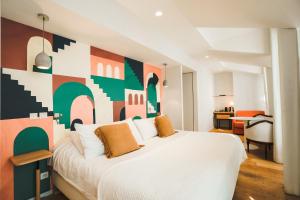 Dormitorio con cama blanca y pared colorida en Hôtel Briketenia, en Guéthary