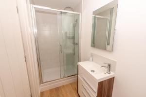 a white bathroom with a shower and a sink at The Sheiling in Woolacombe +6 photos