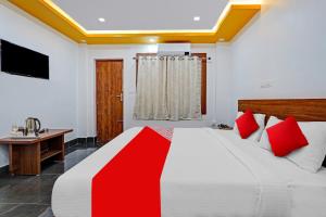 OYO Flagship Vasudha inn, Hoskote في بانغالور: غرفة نوم بسرير كبير ومخدات حمراء