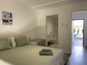 a white bedroom with a bed and a bathroom at The Retreat Fuseta - 3 bed eco villa, own pool in Fuzeta