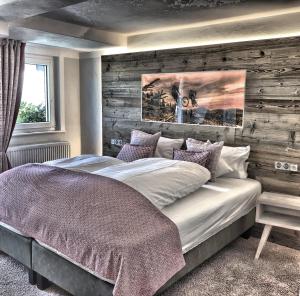 a bedroom with a large bed with a wooden wall at Hotel Nuhnetal in Winterberg