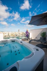 a woman walking on a balcony with a hot tub at The Address Seafront Suites with Hot Tub in Pieta