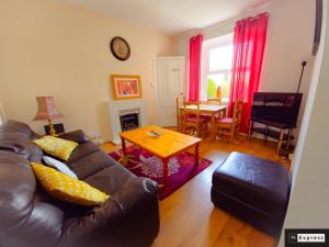 a living room with a leather couch and a table at Two Bedroom Penicuik Apartment in Penicuik