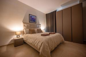 a bedroom with a large bed and a night stand at The Address Seafront Suites with Hot Tub in Pieta