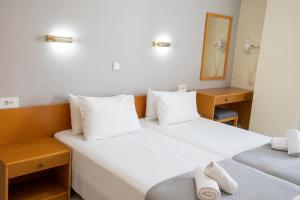 2 bedden in een hotelkamer met witte handdoeken bij Jasmine Hotel in Kos-stad