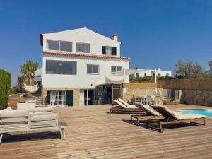 a house with a deck with lounge chairs and a pool at The Lighthouse Hostel Arrifana in Aljezur