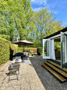 a patio with a table and an umbrella at Woodz Aan de bosrand in Anloo