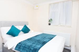 a white bed with blue pillows and a window at Evergreen Apartments-Flat 7, London in London