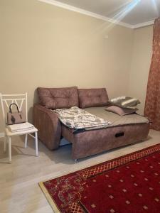 ein Sofa im Wohnzimmer mit einem Bett in der Unterkunft Жк Абырой Ризеденс in Atyrau