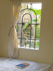 um livro sentado numa cama em frente a uma janela em Mango House Retreat Quy Nhon em Quy Nhon