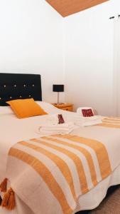 ein Bett mit einer orangefarbenen und weißen Decke drauf in der Unterkunft The Blue House Valley in Grândola