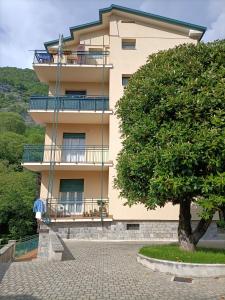 een geel gebouw met een boom ervoor bij Appartamento Maglio in Canzo