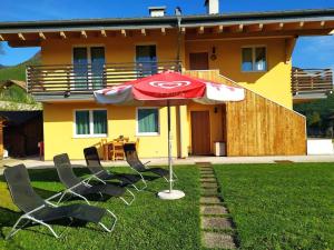 dos sillas y una sombrilla delante de una casa en Il Biancospino Appartamento in Villa, 