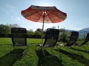 three chairs and an umbrella in the grass at Il Biancospino Appartamento in Villa 