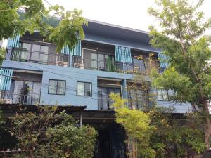 a blue building with balconies and trees at V Tharm Hotel in Udon Thani