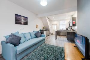 a living room with a blue couch and a tv at Liverpool Harrow Road Sleeps 6- Infinity Apartment in Liverpool