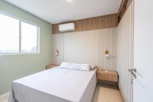 a bedroom with a white bed and a window at Aptos em Bal Piçarras a150m da PRAIA, dois quartos, sala de estar, COZINHA COMPLETA, SACADA com CHURRASQUEIRA, WI-FI, PISCINA, PORTARIA 24h, PLAYGROUND e QUADRA DE ESPORTES in Piçarras