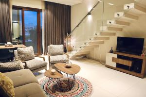 - un salon avec un canapé, une télévision et des escaliers dans l'établissement Casa Salalah, cozy 2-storey townhouse in Hawana Salalah with free Wi-Fi, à Salalah