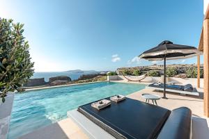 a villa with a swimming pool and an umbrella at Ambeli Sunset Villas in Megalokhori