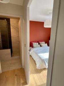 ein Schlafzimmer mit einem Bett und einer roten Wand in der Unterkunft Loft de Juliette à Saint-Malo in Saint-Malo