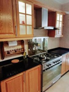 a kitchen with a stove top and wooden cabinets at Apartment with terrace garden in Amman