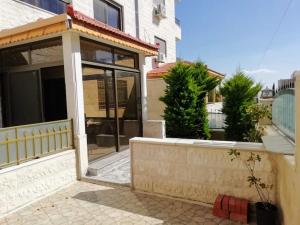 uma casa com uma porta de vidro e uma parede em Apartment with terrace garden em Amã