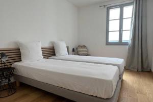 Duas camas num quarto branco com uma janela em D24- T3-Les Hauts du Port-parking-clim-wifi-50m du port em Bonifacio