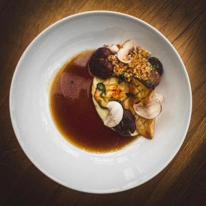 a plate of food with mushrooms and sauce on a table at 2tHEIMAT - Hotel & Restaurant in Morbach
