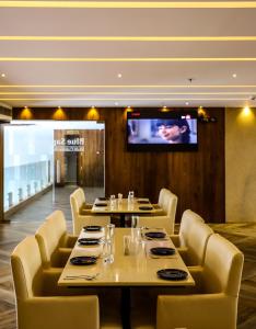 uma sala de jantar com mesas e cadeiras e uma televisão em Hotel The Sea View, Mangalore em Mangalore