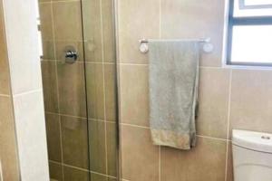 a bathroom with a shower with a white towel at Teasa Stays - Upliving Lifestyle nearby Fourways in Northriding